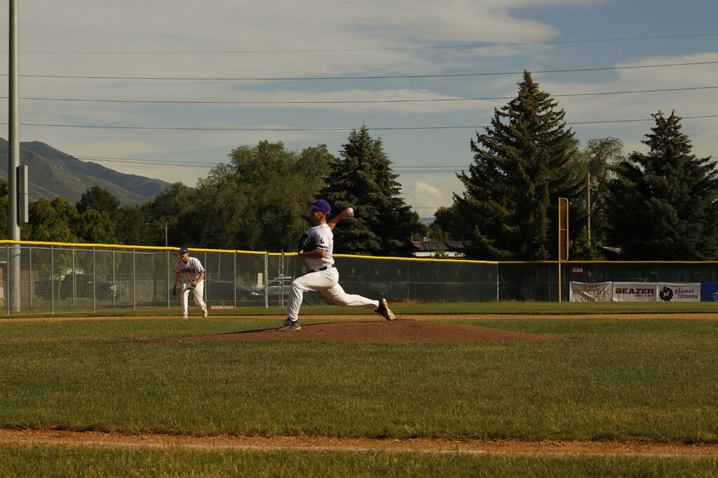 Man in white baseball uniform mid pitch